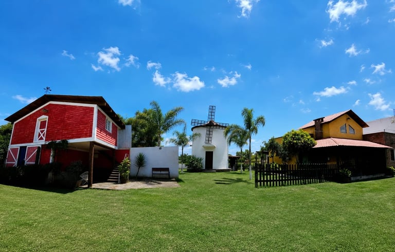 Three colorful rural buildings on a green lawn with palm trees and blue sky in the background